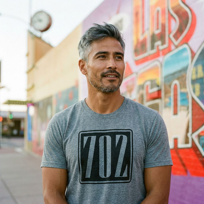 702 Square Las Vegas area code t-shirt in premium heather, worn on a downtown sidewalk beside the Greetings from Las Vegas mural