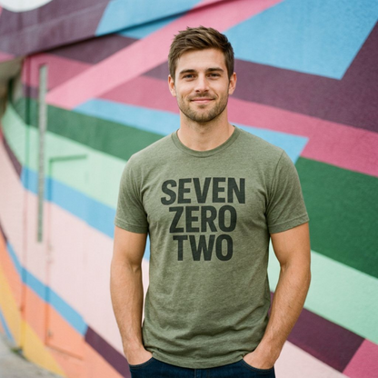 Man wearing the military green Seven Zero Two Las Vegas T-shirt in front of a colorful mural